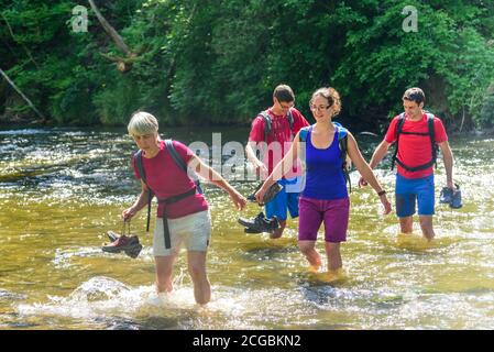 Eine Gruppe von Menschen Waten in einem Flussbett an einem heißen Sommertag im Allgäu Stockfoto