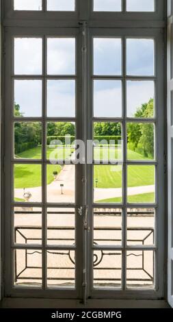 Blick auf den regulären Park durch ein Fenster mit Bars. Sommer Stockfoto