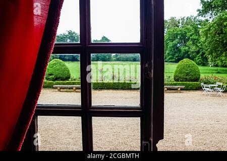 Blick auf den regulären Park durch ein Fenster mit Bars. Sommer Stockfoto