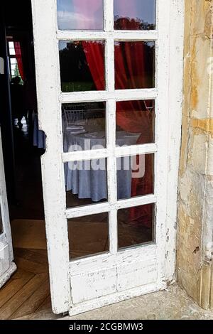 Alte weiße Holztür mit Glas in einem alten Steinhaus. Stockfoto