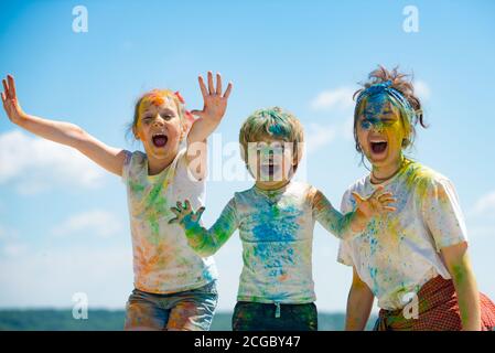 Lustige Kinder Gesicht in Farbe Splash, farbige Pulver auf Kinder Körper. Fröhliche Freunde zeigen Hände in hellen Farben gemalt. Bunte, schmutzige Leute. Stockfoto