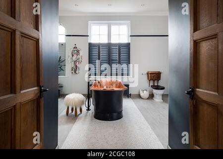 Schwarze, kupfergefütterte, freistehende Badewanne im Badezimmer eines viktorianischen Hauses in South West London, Großbritannien Stockfoto