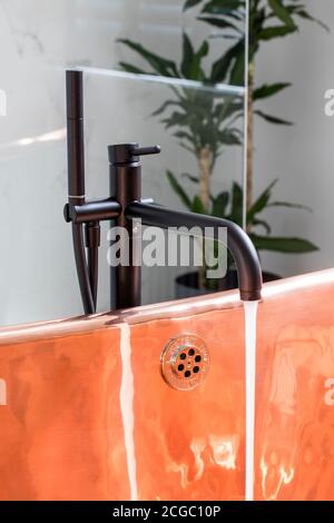 Schwarze, kupfergefütterte, freistehende Badewanne im Badezimmer eines viktorianischen Hauses in South West London, Großbritannien Stockfoto