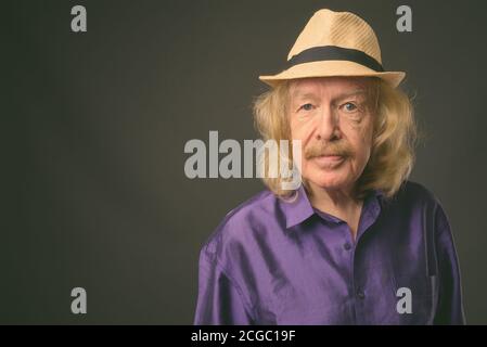 Senior touristische Mann mit Schnurrbart gegen grauer Hintergrund Stockfoto