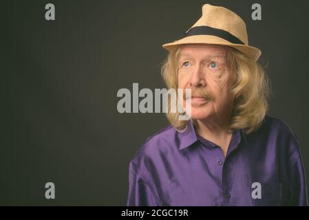 Senior touristische Mann mit Schnurrbart gegen grauer Hintergrund Stockfoto