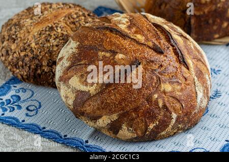 Ein handgemachtes Brot loafs auf einem blauen Tuch Serviette. Hausgemachtes Brot mit Samen aus Sauerteig Stockfoto