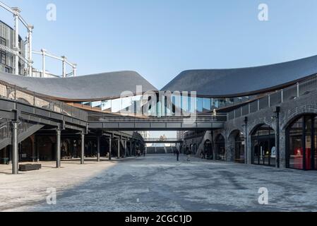 Coal Drops Yard by Heatherwick Studio ist ein Einzelhandelsviertel in London King's Cross, Großbritannien. Abgeschlossen im Jahr 2018 ist es ein adaptives Wiederverwendung Projekt der ehemaligen Kohlelager.Wilkinson Eyre's Gasholders im Hintergrund. Stockfoto