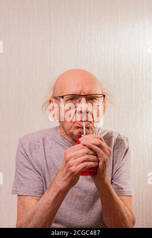 Durch ein Rohr von Flüssigkeit aus einem roten Glas unter den Tabletten. Blick von vorne. Vertikale Aufnahme. Stockfoto