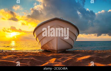 Tropische Seascape mit einem Boot auf Sandstrand bei bewölkt sonnenaufgang oder Sonnenuntergang Stockfoto