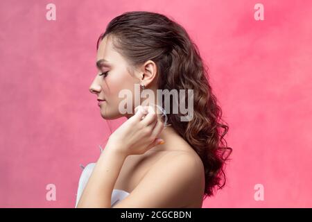 Porträt einer jungen schönen Frau in eleganten weißen, strukturierten rosa Hintergrund. Die Braut mit einem leichten und stilvollen Styling. Schöne junge Brünette. Stockfoto