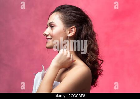 Porträt einer jungen schönen Frau in eleganten weißen, strukturierten rosa Hintergrund. Die Braut mit einem leichten und stilvollen Styling. Schöne junge Brünette, Stockfoto