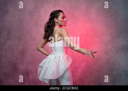 Porträt einer jungen schönen Frau in einem eleganten weißen Anzug, strukturierte rosa Hintergrund. Braut in einem modernen Stil Stockfoto
