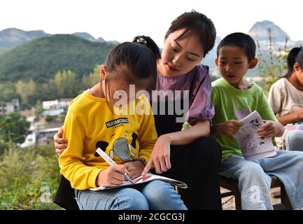 (200910) -- LINGCHUAN, 10. September 2020 (Xinhua) -- Chen Yanzi bringt Schüler aus dem Klassenzimmer, um in dem Dorf Mawuzhai der Gemeinde Gujiao des Landkreises Lingchuan, Stadt Jincheng, nordchinesische Provinz Shanxi zu zeichnen, 8. September 2020. In den Tiefen des Taihang-Gebirges, mehr als 1,300 Meter über dem Meeresspiegel gelegen, ist die Mawuzhai Internat-Grundschule mit ihren ganzen sechs Schülern die einzige Schule im Umkreis von Dutzenden von Kilometern. Chen Yanzi kam im Alter von 25 Jahren im September 2019 hierher und wurde Lehrer. Chen Yanzi kam aus der Innenstadt von Jincheng und es dauerte mehr als drei Stunden Stockfoto