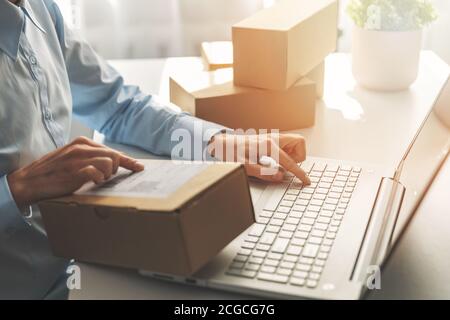 Person, die Bestellungen im Online-Shop für den Versand mit einem Laptop vorbereitet Stockfoto