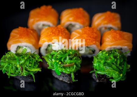 Sushi-Set mit Lachs. Sushi-Rolle Philadelphia mit rotem Fisch, Lachs, rotem Kaviar. Rollen Sie mit weicher Avocado und Frischkäse unter einer Schicht Massago Kaviar Stockfoto
