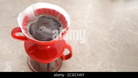 Pourover v60. Der köstliche aromatische Kaffeefilter wird in einem roten Keramiktropfer gebrüht. Nahaufnahme, Ansicht von oben Stockfoto