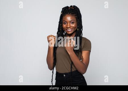 Aufgeregt glücklich junge afroamerikanische Frau Gefühl überglücklich isoliert auf grauen Studio-Hintergrund. Glückliches euphorisches schwarzes Mädchen Gewinner feiern Sieg Stockfoto