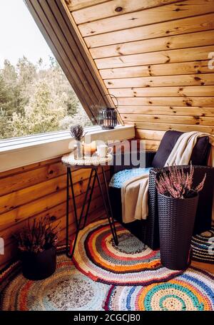 Niedliche Herbst Hygge Home Dekor Anordnung. Winziger Holzbalkon mit Heideblumen im Topf, Lavendel in Flaschenvase, Kerzenflamme, Karloster. Stockfoto