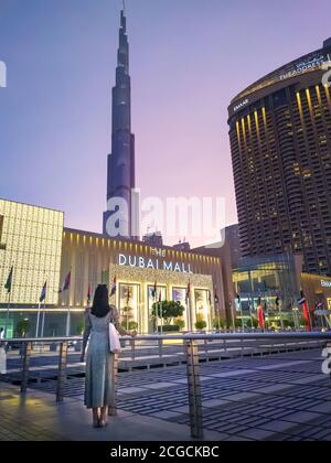 Dubai, Vereinigte Arabische Emirate - 25. August 2020: Frau steht vor dem Haupteingang des Dubai Mall mit Burj Khalifa im Hintergrund. Stockfoto