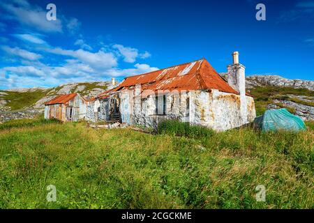 Eine alte zerstörte Croft mit einem rostigen roten Blechdach In Quidnish auf der Isle of Harris in der Outer Hebriden von Schottland Stockfoto