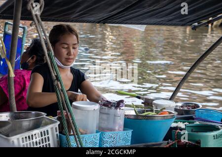 BANGKOK, THAILAND, JULI 18 2020, EINE Frau kocht Essen auf dem Boot in einem Wasserkanal, Khlong Lat Mayom Floating Market. Stockfoto