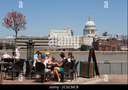 Menschen genießen ein Mittagessen im Freien am Südufer der Themse, mit St. Paul's Cathedral in der Ferne, London, England. Stockfoto