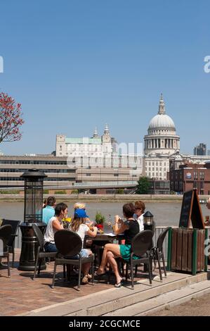 Menschen genießen ein Mittagessen im Freien am Südufer der Themse, mit St. Paul's Cathedral in der Ferne, London, England. Stockfoto