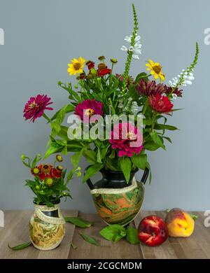 Stillleben mit Blumen und Früchten. Ein kleines Bouquet aus verschiedenen Blumen und reifen Pfirsichen. Vintage. Stockfoto