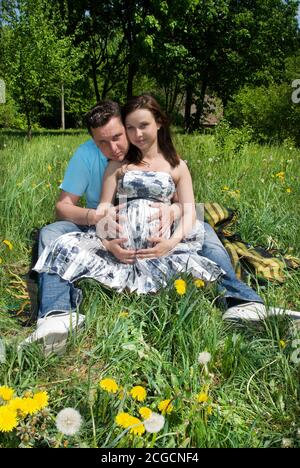 Ein Mann mit einer schwangeren Frau auf einer Wiese Stockfoto