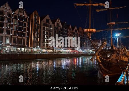 Danzig, Nordpolen - 13. August 2020: Nachtfoto der mittelalterlichen polnischen Architektur und ein Piratenschiff über dem fluss motlawa in der Altstadt Stockfoto