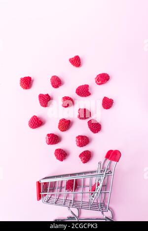 Himbeeren fallen in den Warenkorb auf rosa Hintergrund. Gesunde Mahlzeiten einkaufen, Füllhorn und Wellness-Konzept Stockfoto