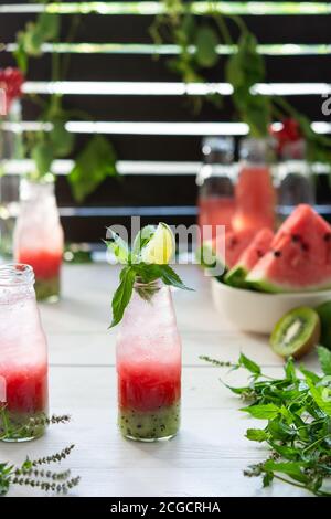 Kalt erfrischender Wassermelonensaft, Wassermelone mit Kiwi und Eis in Flaschen, Obst-Smoothie auf Holzhintergrund Stockfoto