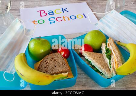 Zurück in die Schule während Corona - Lunchbox mit gesunden Mahlzeit und Mundschutz Maske Stockfoto