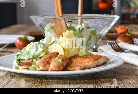Gebratener Fisch mit Kartoffelpüree und Salat - deutsches Rezept Serviert auf einem weißen Teller Stockfoto