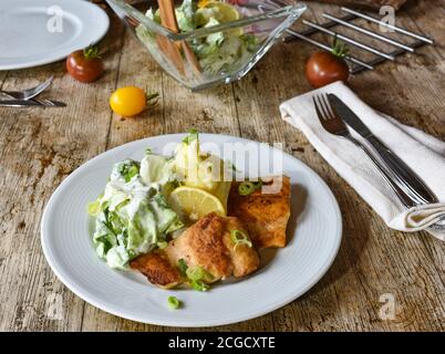 Gebratener Lachs mit Kartoffelpüree und Salat auf einem weißen Platte Stockfoto