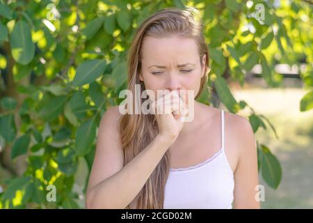 Sommer im Garten. Jung EINE Frau hustet wegen Pollenallergie. Stockfoto