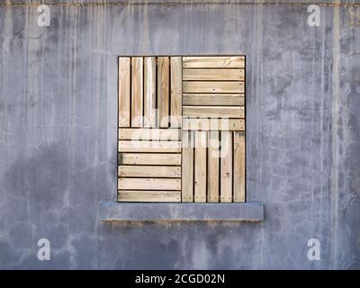 Alte Industriefenster mit Holzpaneelen in grau geschlossen Zementwand Stockfoto
