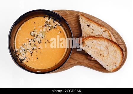 Traditionelle Herbstgemüsesuppe mit Kürbis und Sesam und Zwei Scheiben geröstetes Brot auf Holzbrett Draufsicht Stockfoto