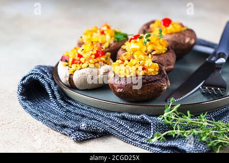 Gebackene gefüllte portobello-Pilze mit Bulgur-Pilaf und gehacktem Gemüse. Leckeres und nahrhaftes vegetarisches Gericht. Steinhintergrund. Stockfoto