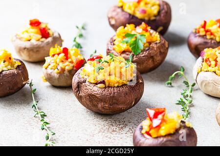 Gefüllte portobello-Pilze mit Bulgur, Gemüse und aromatischen Kräutern auf betontem Hintergrund. Vegetarisches Essen. Stockfoto