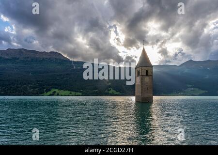 Die Sonne untergeht hinter dem berühmten unter Wasser liegenden Glockenturm im Reschensee, Graun Vinschgau, Südtirol, Italien Stockfoto