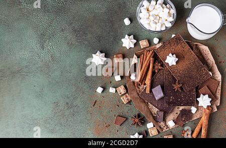Zutaten für die Herstellung von heißer Schokolade. Dunkle und milchige Schokolade, Kakaopulver, Zimt, Anisstern, brauner Zucker, Marshmallow, Baiser und Milchüberzug Stockfoto
