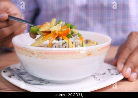 Nahaufnahme eines jungen Mannes, der Gemüsesuppe isst Stockfoto