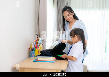 Asiatische nette Grundschulmädchen und ihre Mutter Verpackung ihre Schultaschen, die Vorbereitung für den ersten Tag der Schule. Die morgendliche Schulroutine für Tag in Stockfoto