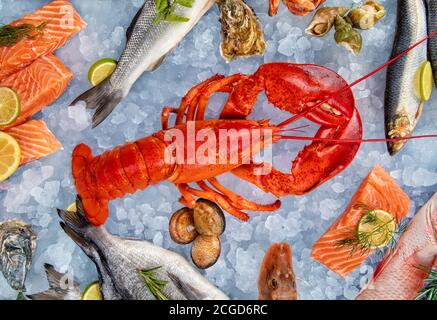 Hummer mit Meeresfrüchten, Krabben, Muscheln, Garnelen, Fisch, Lachssteak, Oktopus, Auster und anderen Muscheln auf zerkleinerten Eis und Holztisch serviert Stockfoto