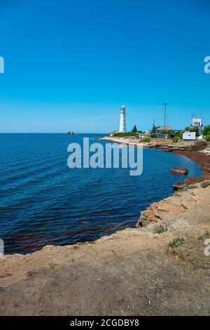 Blaues Meer Landschaft mit weißem Leuchtturm auf Vorland Stockfoto