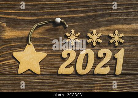 Neujahr 2021. Goldene Zahlen und Dekorationen in Form von Sternen und Schneeflocken auf einem dunklen Holztisch. Frohe Weihnachten und Frohes neues Jahr. Speicherplatz kopieren Stockfoto