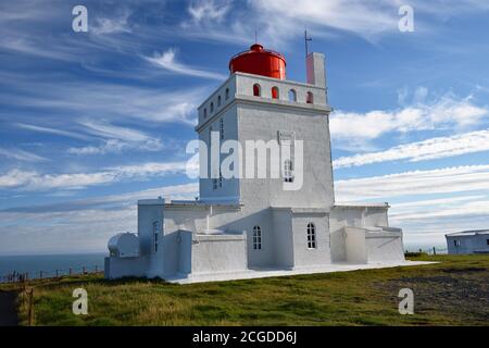 Ein abstrakter Blick nach oben auf den Leuchtturm von Dyrhólaey entlang der Südküste Islands. Ein weißer Leuchtturm mit kontrastierendem roten Laternenhaus. Stockfoto