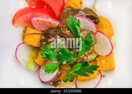 Makro-Foto von Salat mit gebratener Hühnerleber, Rettich, Kürbis, Tomate und Senf Stockfoto