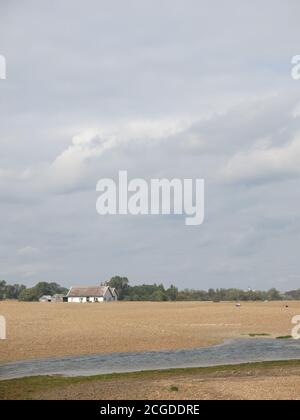 East Anglia ist bekannt für seinen großen Himmel und seine verlassenen Landschaften; ein isoliertes Ferienhaus am Strand an der Shingle Street, Suffolk. Stockfoto